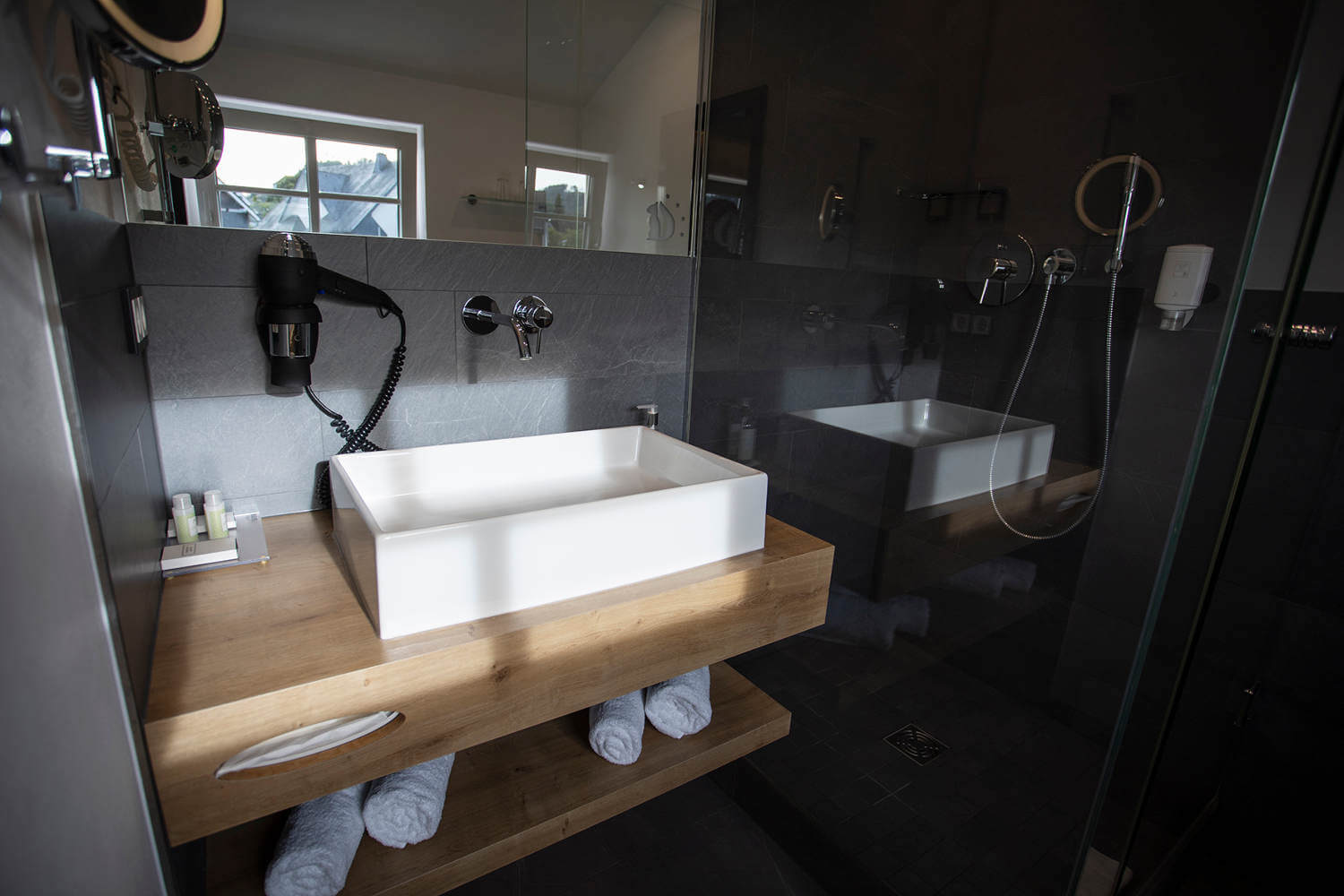 Waschtisch und mit Glasscheibe abgetrennter Duschbereich im Doppelzimmer "Stammhaus Premium Plus Straßenseite", Hotel Diedrich im Sauerland