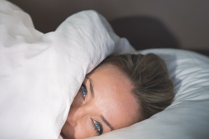 Frau kuschelt sich gemütlich in die Bettdecke im Wellnesshotel Diedrich im Sauerland