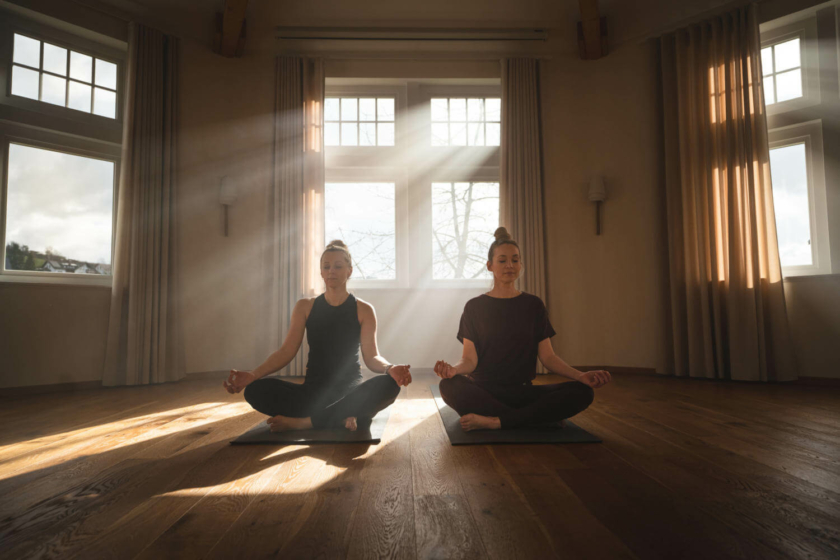 Zwei Frauen beim Yoga im Meditationsraum des Wellnesshotels Diedrich im Sauerland, meditieren im Morgenlicht